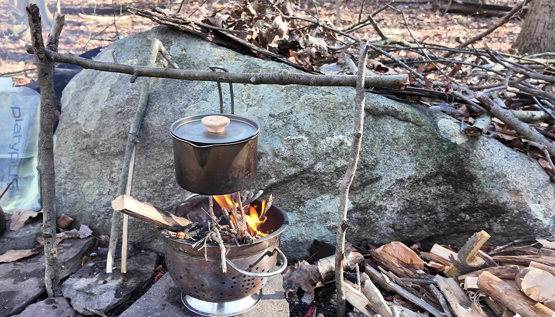 Stirring a bubbling pot over open flames—the wilderness kitchen in action.