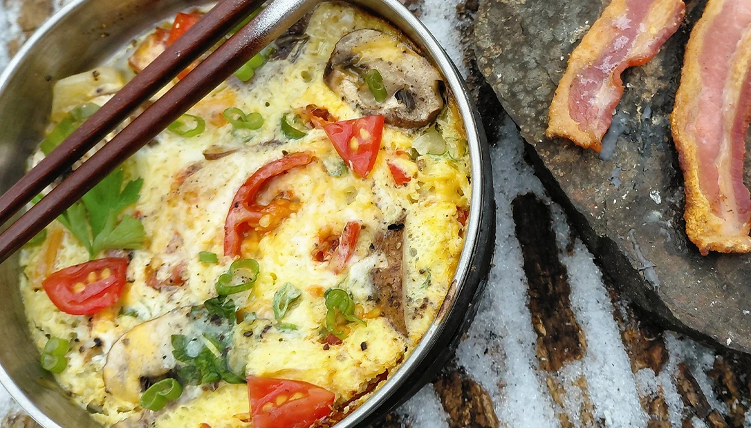 Fresh omelet ingredients are ready to be mixed and steamed using lightweight camp gear.
