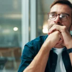 A solitary figure gazes at a wall of closed books, symbolizing the end of questioning in the age of certainty.