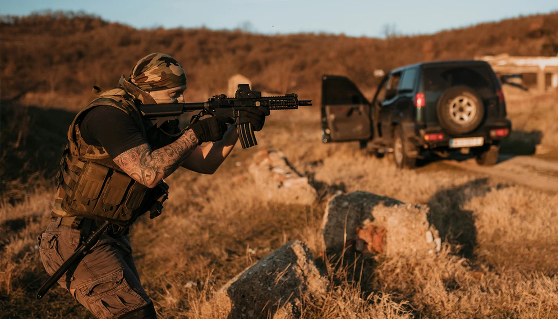 Private military contractors in tactical gear providing security near a vehicle in a desert environment.